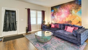 A living room with a dark blue sofa, a glass coffee table, and a colorful abstract painting on the wall. - Pet-friendly Davenport Home - Near Casino & Golf (Davenport)