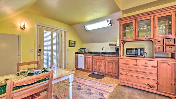 A kitchen with wooden cabinets, a microwave, and a dining area with a table and chairs. - Riverside Tree House Suite w/ Balcony & Grill (Payson)