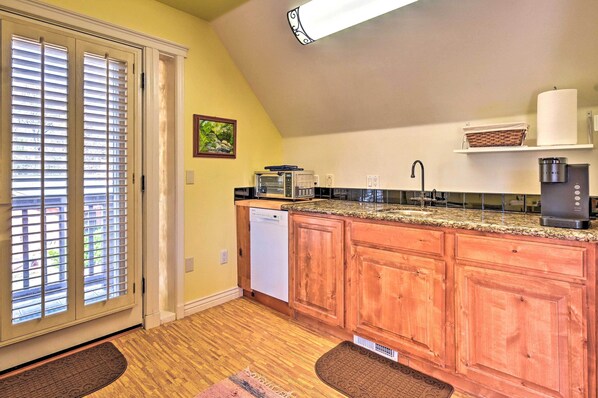 A kitchen with wooden cabinets, a microwave, a dishwasher, and a coffee maker. - Riverside Tree House Suite w/ Balcony & Grill (Payson)
