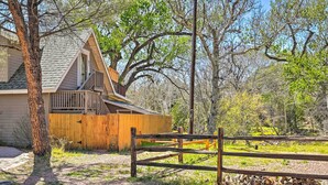A wooden cabin with a balcony, surrounded by trees and a wooden fence. - Riverside Tree House Suite w/ Balcony & Grill (Payson)