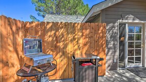 A backyard with a wooden fence, a barbecue grill, and a small table. - Riverside Tree House Suite w/ Balcony & Grill (Payson)