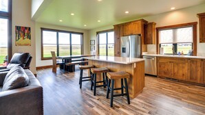 Una cocina amplia con armarios de madera, un refrigerador de acero inoxidable y una barra con taburetes.