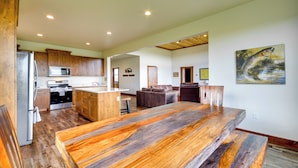 Una cocina amplia con armarios de madera, una isla grande y un comedor con una mesa de madera larga.