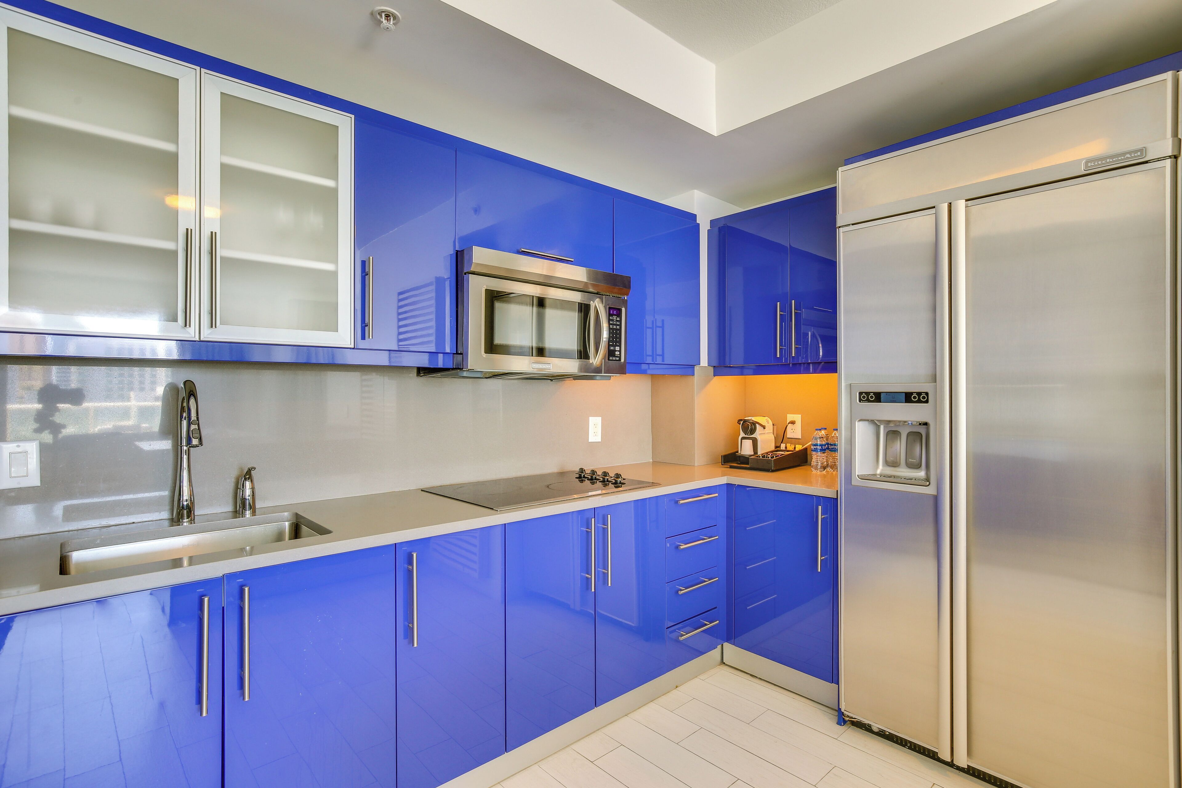 Una cocina moderna con armarios azules, electrodomésticos de acero inoxidable y un microondas integrado.