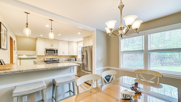 A modern kitchen with a central island, bar stools, and a dining table with chairs. - Saratoga Springs Home Near Skidmore College! (Saratoga Springs)