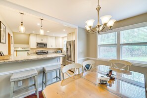 A modern kitchen with a central island, bar stools, and a dining table with chairs. - Saratoga Springs Home Near Skidmore College! (Saratoga Springs)