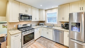 A modern kitchen with stainless steel appliances, white cabinetry, and a granite countertop. - Saratoga Springs Home Near Skidmore College! (Saratoga Springs)