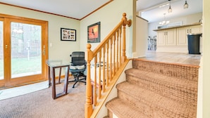 A home interior with a staircase leading to a kitchen, a dining area with a table and chairs, and a large window with a view of the outdoors. - Saratoga Springs Home Near Skidmore College! (Saratoga Springs)