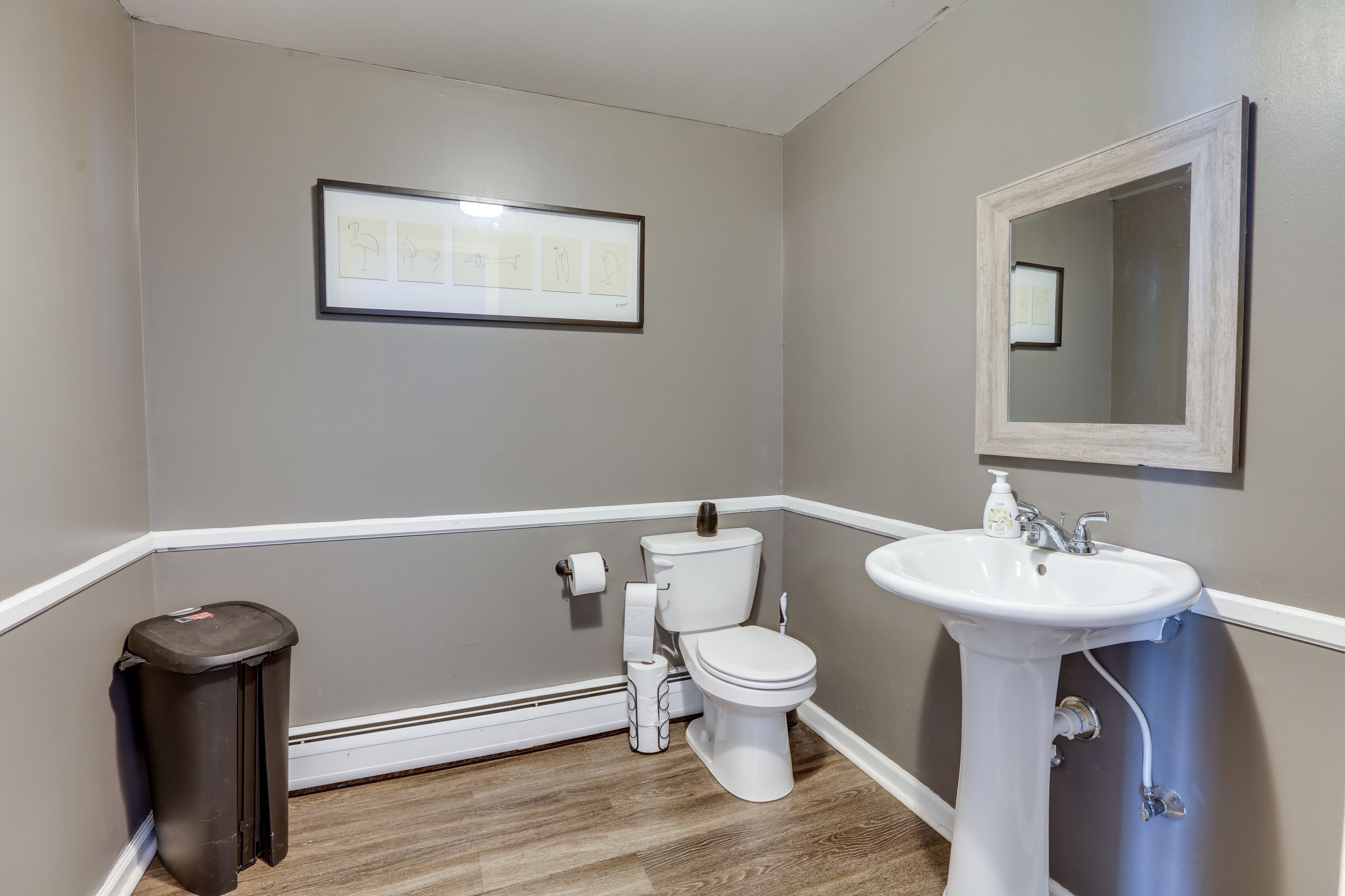 A bathroom with a toilet, sink, and trash can.