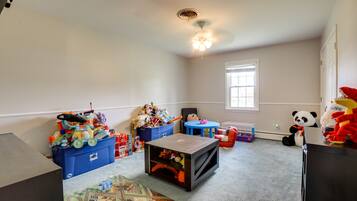 A child's playroom with toys, a ceiling fan, and a window.