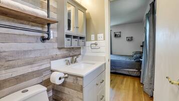 A bathroom with a wooden wall, a white sink, a mirror, and a toilet.