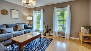 A spacious living room with a blue sofa, a wooden coffee table, and a patterned rug. - Dog-friendly Freeville Home ~ 8 Mi Cayuga Lake! (Freeville)