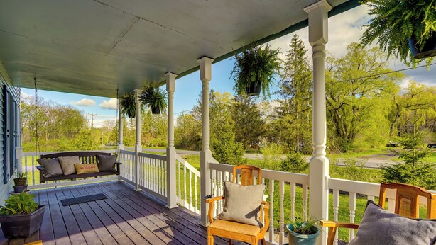 A wooden porch with a bench and chairs, potted plants, and a view of the surrounding greenery. - Dog-friendly Freeville Home ~ 8 Mi Cayuga Lake! (Freeville)