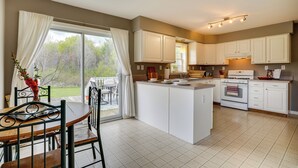 A spacious kitchen with white cabinets, a central island, and a dining area with a table and chairs. - Dog-friendly Freeville Home ~ 8 Mi Cayuga Lake! (Freeville)