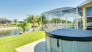 A covered outdoor area with a pool, palm trees, and a view of a body of water. - Near Sand & Sun, Cape Coral Home w/ Private Pool (Cape Coral)