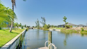 A calm waterway with a wooden dock and a concrete walkway on the left. - Near Sand & Sun, Cape Coral Home w/ Private Pool (Cape Coral)