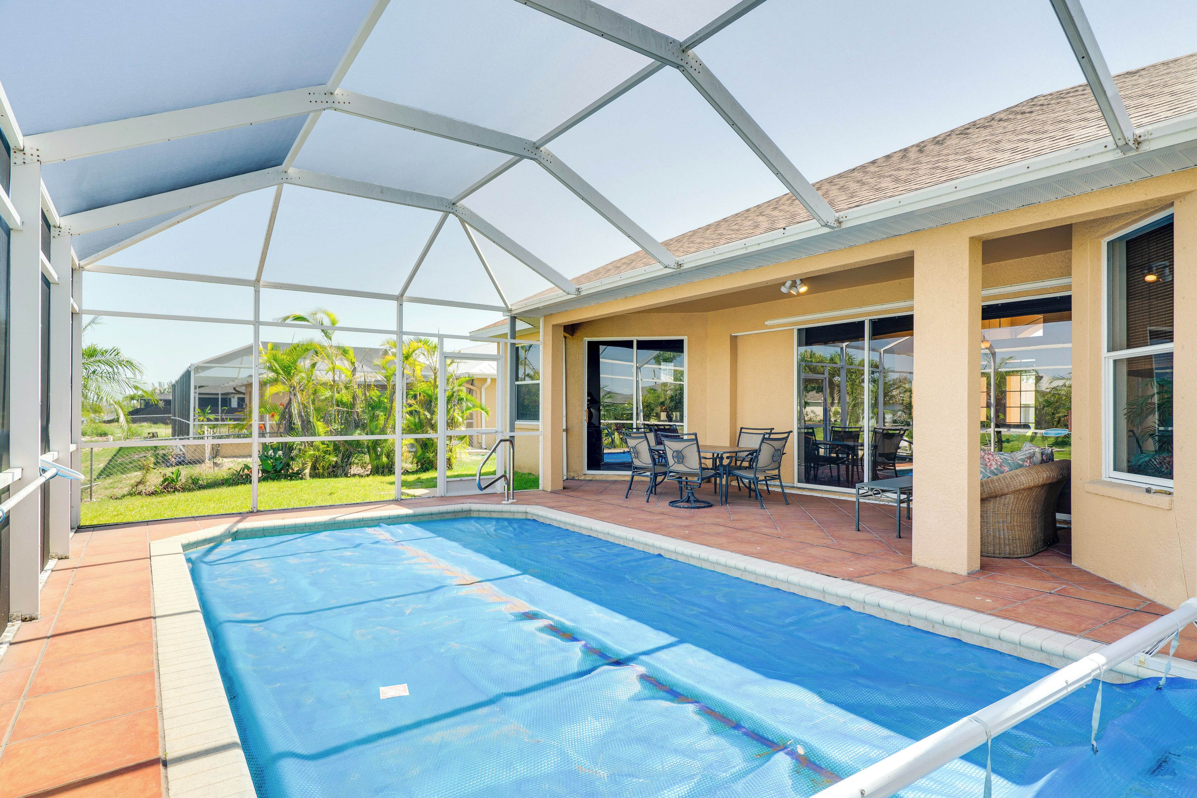 Una piscina exterior techada con zona de patio, que incluye sillas y una mesa.