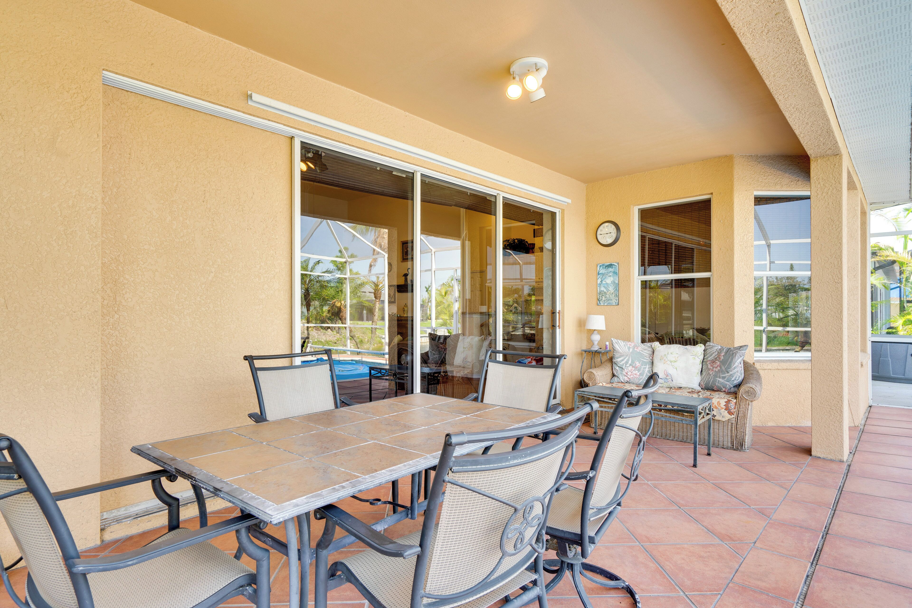 An outdoor patio with a dining table and chairs, a sofa, and a window with blinds.