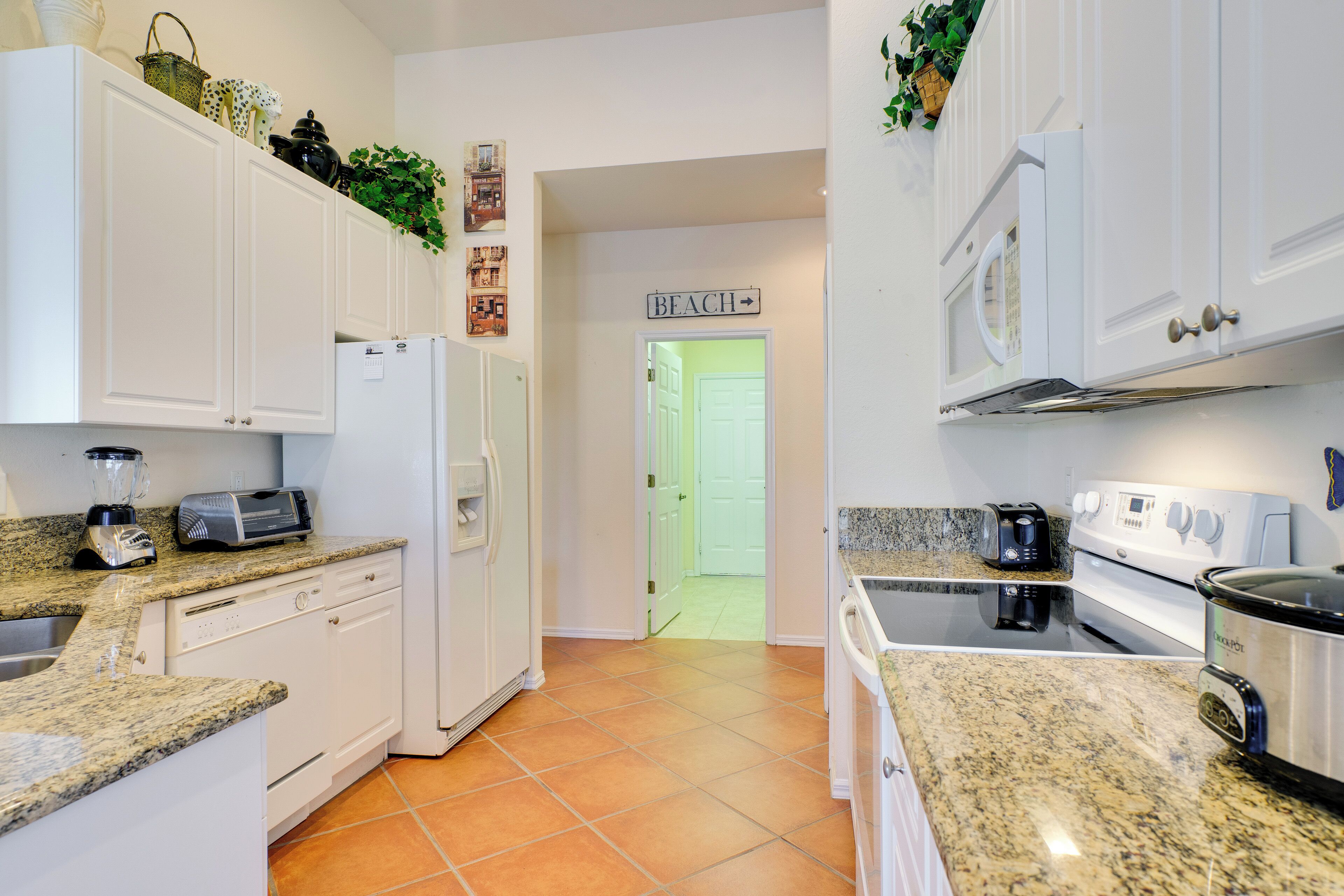 A kitchen with white cabinets, a granite countertop, a refrigerator, a stove, and a microwave.