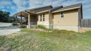 A single-story house with a covered porch, a stone foundation, and a wooden fence. - New Braunfels Home w/ Pool 2 Mi to Guadalupe River (New Braunfels)