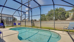Ein überdachter Pool mit blauem Wasser, umgeben von einer Metallkonstruktion und Glasscheiben, mit Liegestühlen und einer Person darin.