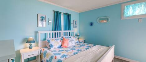 A bedroom with a bed, nightstands, a window with curtains, and wall decorations.