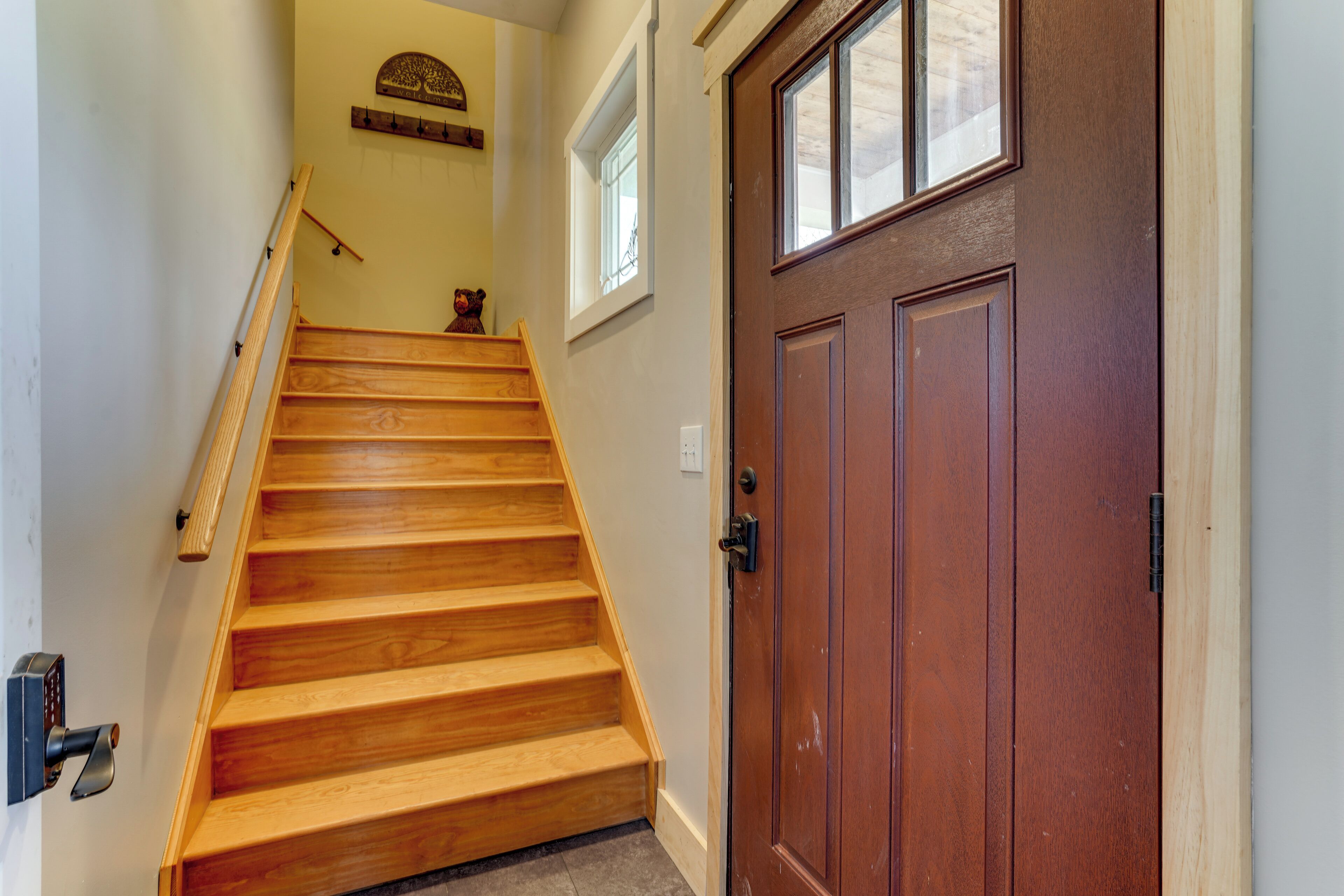 A wooden staircase leading to a brown door with a window above it.