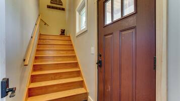 A wooden staircase leading to a brown door with a window above it.