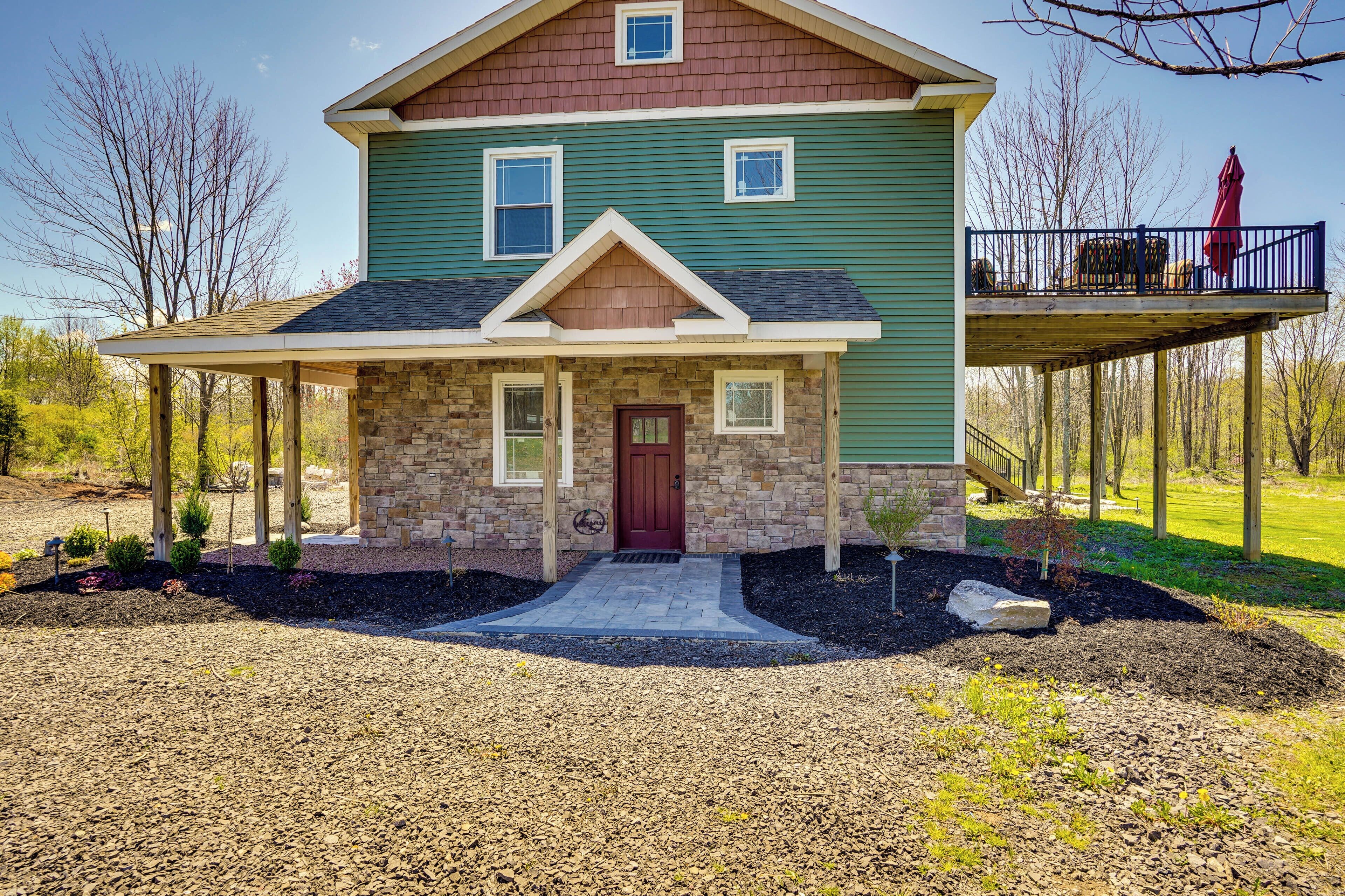 A two-story house with a stone front, a red door, and a covered porch.