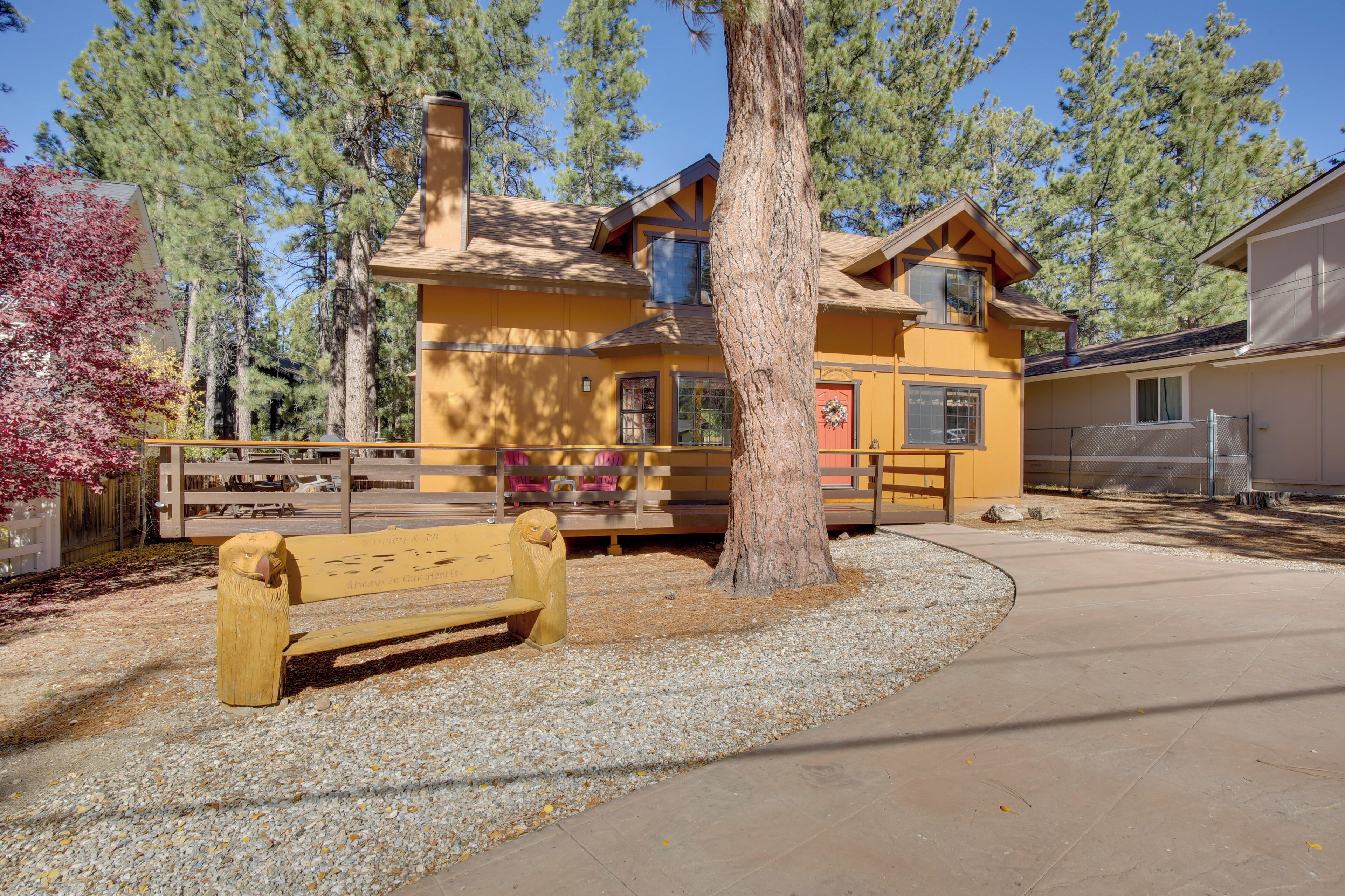 A yellow lodge with a wooden bench and a tree in front.