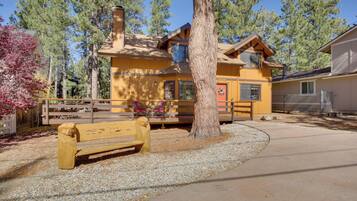 A yellow lodge with a wooden bench and a tree in front.
