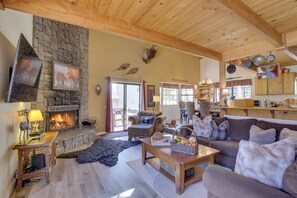 A cozy living room with a stone fireplace, wooden ceiling beams, and a comfortable seating area. - Dancing Bear Lodge ~ 1 Mi to Big Bear Lake! (Big Bear Lake)