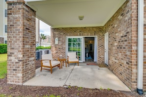 A covered patio area with brick walls, a concrete floor, and a sliding glass door leading to a garage. - 3 Mi to Ocean: Modern Myrtle Beach Vacation Rental (Myrtle Beach)