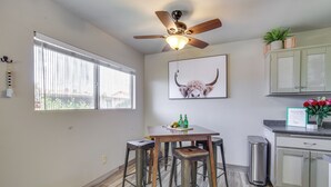 Une cuisine avec un ventilateur de plafond, une fenêtre, un tableau représentant un taureau et une pancarte de bienvenue.