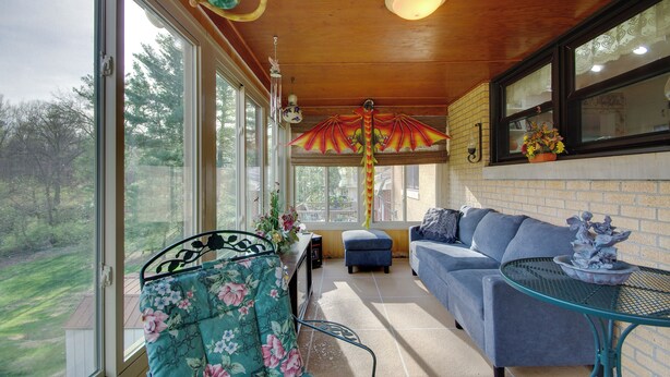 A sunroom with a blue sofa, a green metal table, and a view of a garden. - Charming Jefferson City Home: 2 Mi to Downtown! (Jefferson City)