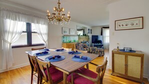 A dining area with a wooden table set for four, surrounded by chairs with red cushions. A chandelier hangs from the ceiling, and a fish tank is visible in the background. - Charming Jefferson City Home: 2 Mi to Downtown! (Jefferson City)
