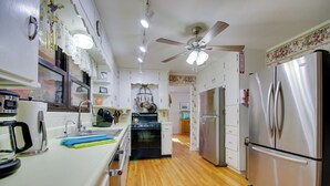 A kitchen with wooden flooring, stainless steel appliances, a ceiling fan, and white cabinetry. - Charming Jefferson City Home: 2 Mi to Downtown! (Jefferson City)