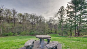 A stone picnic table with two benches in a grassy area surrounded by trees. - Charming Jefferson City Home: 2 Mi to Downtown! (Jefferson City)