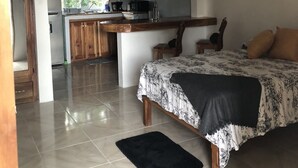 A bedroom with a bed, a black rug, and a wooden headboard. - Seacret Studios - Cozy Jamaican Retreat Apts by RedAwning (Negril)