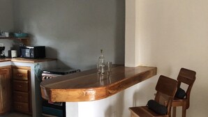 A kitchen with a wooden island, two bar stools, a microwave, and a gas stove. - Seacret Studios - Cozy Jamaican Retreat Apts by RedAwning (Negril)