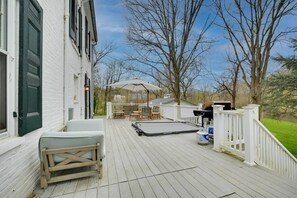 A wooden deck with outdoor furniture, a grill, and a white fence.