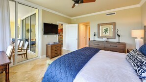 Une chambre dotée d’un grand lit, d’un ventilateur de plafond, d’une télévision et d’une porte-fenêtre coulissante donnant sur un balcon.