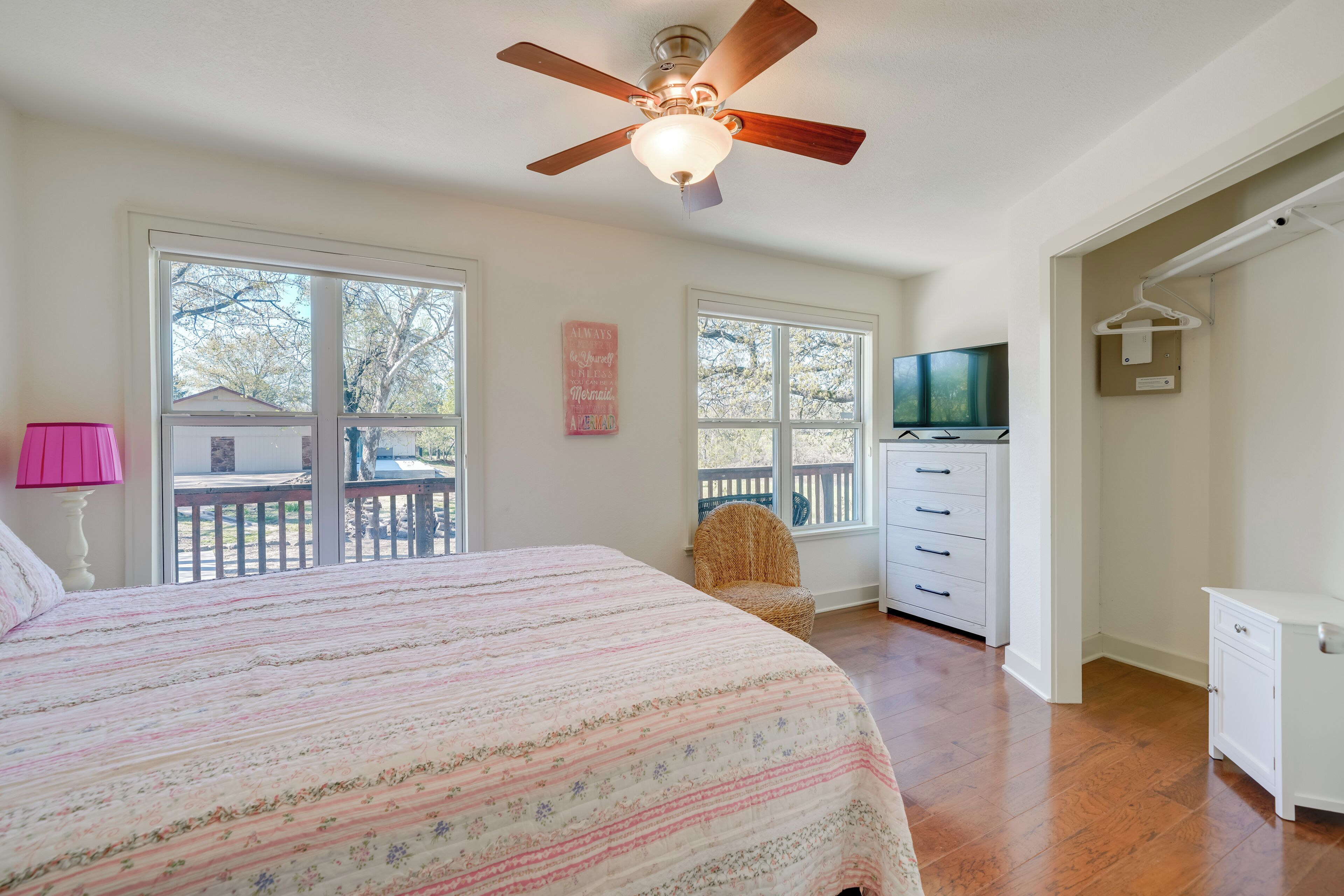 Une chambre à coucher avec un grand lit, un ventilateur de plafond, une télévision, une chaise et une commode.