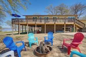 A building with a deck, outdoor seating with Adirondack chairs, and a fire pit. - Spacious Vacation Rental Home on Eufaula Lake! (Eufaula)