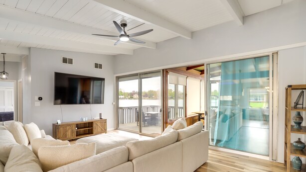 A spacious living room with a large sectional sofa, a flat-screen TV, and a ceiling fan. - Riverfront Elkhart Rental: Deck & Ping Pong Table! (Elkhart)