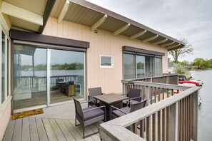 A balcony with a table and chairs, a sliding glass door, and a view of a river. - Riverfront Elkhart Rental: Deck & Ping Pong Table! (Elkhart)