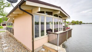 A waterfront building with a covered deck, large windows, and a satellite dish. - Riverfront Elkhart Rental: Deck & Ping Pong Table! (Elkhart)