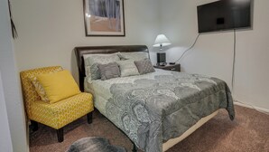 A bedroom with a bed, a chair, a TV, and a lamp. - Peaceful Peoria Vacation Rental: Near Westgate! (Peoria)