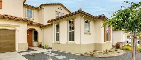 A two-story house with a garage, a front entrance, and a small garden area with stepping stones.