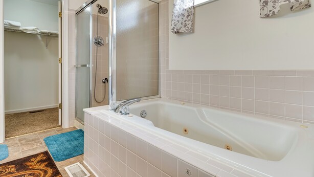 A bathroom with a white bathtub, a glass shower enclosure, and a towel rack with towels. - Indianapolis Rental Home w/ Gym: Near Speedway! (Indianapolis)